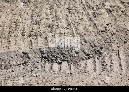 Sandgrunge-Textur mit Spuren von schweren Geräten auf einer Baustelle Stockfoto