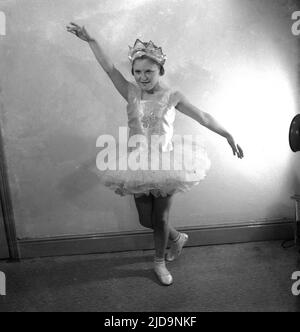 1950s, historisch, ein junges Mädchen, Balletttänzerin in ihrem Kostüm - bekannt als Tutu - und Kopfkrone, posiert in einem Studio unter Spotlights, Stockport, Manchester, England, UK. Stockfoto