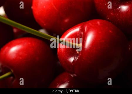 Süße Kirsche und ihr Stiel bei schwachem Licht. Selektiver Fokus. Stockfoto