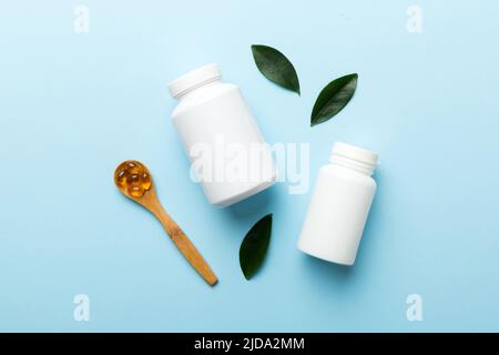 Omega-3 Kapseln liegen in einer weißen Flasche auf einem Tisch mit grünem Blatthintergrund. Fischöltabletten. Biologisch aktive Zusatzstoffe. omega 6, Omega 9, Vitam Stockfoto