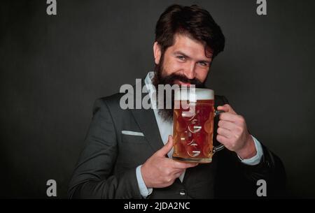 Das Festkonzept des oktoberfests. Mann im schwarzen Anzug trinkt Bier. Lager und dunkles Bier. Stockfoto