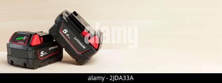 Lithium-Akku für Akku-Bohrmaschine. Schrauberbatterie. Vier Batterien mit Ladeanzeige liegen auf einem Holzhintergrund Stockfoto