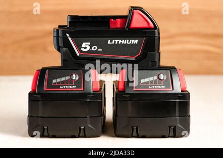 Lithium-Akku für Akku-Bohrmaschine. Schrauberbatterie. Vier Batterien mit Ladeanzeige liegen auf einem Holzhintergrund Stockfoto