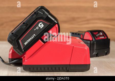 Der Vorgang, bei dem eine Lithiumbatterie von einem kabellosen Bauwerkzeug geladen wird. Der Akku des Schraubendrehers wird im Ladegerät geladen Stockfoto