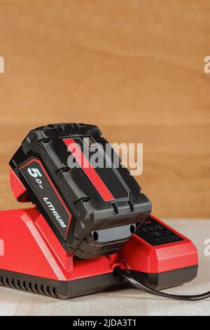 Der Vorgang, bei dem eine Lithiumbatterie von einem kabellosen Bauwerkzeug geladen wird. Der Akku des Schraubendrehers wird im Ladegerät geladen Stockfoto