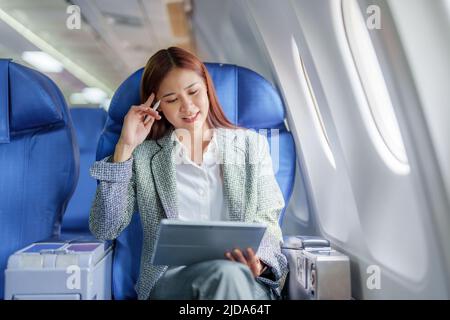 Reisen, Porträt einer asiatischen Geschäftsfrau, die während der Wartezeit im Flugzeug mit einem Tablet-Computer plante, um Geschäfte mit dem Ausland zu verhandeln Stockfoto