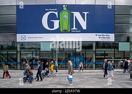 Einkäufer, die an einer Werbung für alkoholfreien Gin im Omni Centre in Edinburgh, Schottland, Großbritannien, vorbei gehen. Stockfoto