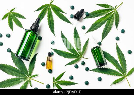 Draufsicht auf grüne Hanfblätter mit wiederverwendbaren Flaschen aus Kosmetikglas. Medizinische und Freizeitnutzung von Marihuana. Naturkosmetik oder Superfood Stockfoto