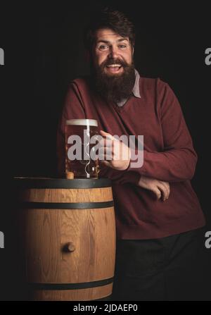 Mann mit Bier. Deutschland - Bayern. Bier. Fröhlicher Mann mit Bier und Holzfass und einem Glas Bier. Stockfoto
