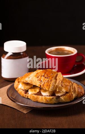 Knuspriges Croissant mit Erdnussbutter, Banane und duftendem Kaffee Stockfoto