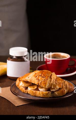 Knuspriges Croissant mit Erdnussbutter, Banane und duftendem Kaffee Stockfoto