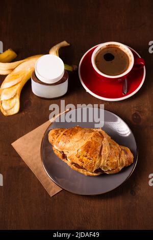 Knuspriges Croissant mit Erdnussbutter, Banane und duftendem Kaffee Stockfoto