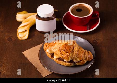 Knuspriges Croissant mit Erdnussbutter, Banane und duftendem Kaffee Stockfoto