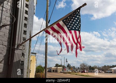 Zerfetzte amerikanische Flagge, die auf einem Gebäude an der Main Street fliegt. Stockfoto