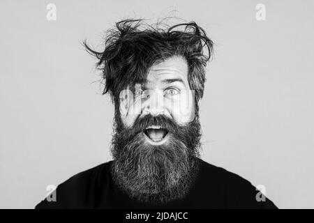 Überraschte einen schönen Mann. Schockiert männlichen Modell mit überraschenden Ausdruck, wow begeistert aufgeregt Gesicht. Emotionen Menschen Konzept. Bärtiger lustiger Hipster. Stockfoto