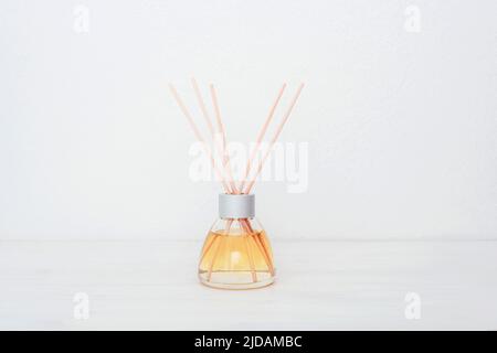 Glasflasche mit Aroma-Diffusor auf weißem Hintergrund. Minimalistisches Design der Inneneinrichtung. Nahaufnahme, Kopierbereich. Stockfoto
