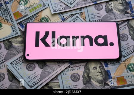 Klarna App-Logo auf dem Bildschirm des Smartphones auf Dollarscheine platziert gesehen. Konzept für Credit App. Stafford, Großbritannien, Juni 19 2022 Stockfoto