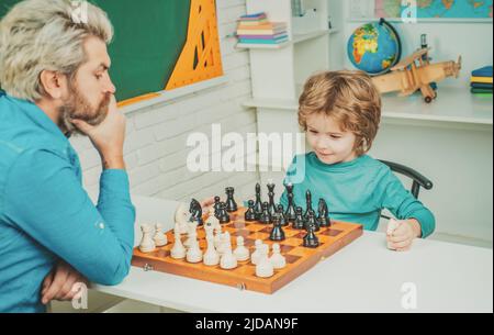 Vatertag. Konzentrierter Junge, der eine Schachstrategie entwickelt. Cleveres, konzentriertes und denkendes Kind beim Schachspielen. Stockfoto