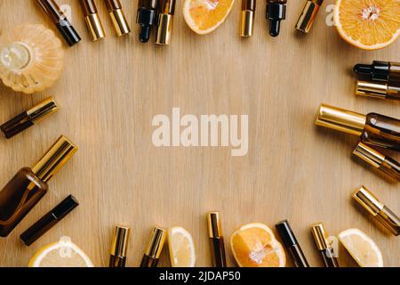 Ätherisches Öl in Flaschen und Zitronen, Orangen auf einer Holzoberfläche. Stockfoto