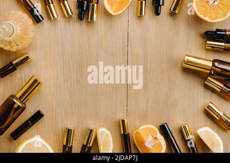 Ätherisches Öl in Flaschen und Zitronen, Orangen auf einer Holzoberfläche. Stockfoto