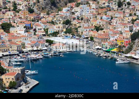 Überblick über das Stadtzentrum von Symi und Boote, die am Ufer im Yachthafen am Hafen von Gialos auf der Insel Symi (Simi) vor Anker liegen Stockfoto