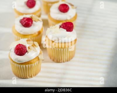 Appetitliche Muffins mit Rahm und Himbeeren. Isoliert auf weißem Hintergrund. Süßes Essen, viele Kalorien. Urlaub, Geburtstag. Restaurant, Hotel, Café, Stockfoto
