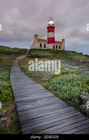 Holzsteg über das Moorland, der zum Cape Agulhas Leuchtturm am Cape Agulhas führt, dem südlichsten Punkt des afrikanischen Kontinents und... Stockfoto