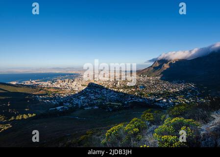 Wolkenformation, die den Tischdecken-Effekt über dem Tafelberg erzeugt, mit einem Überblick über die Skyline von Kapstadt vom Signal Hill und der Löwenkopfhalterung... Stockfoto