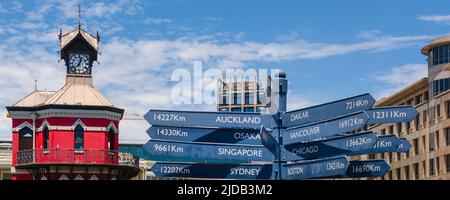 Alter Uhrenturm und Wegweiser, Wegweiser mit der Entfernung zu verschiedenen Orten an der Victoria und Alfred Waterfront in Kapstadt Stockfoto