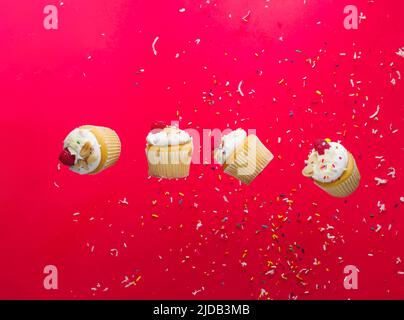 Appetitliche kleine Beerenmuffins mit Himbeeren im gefrorenen Flug auf einem rosa Hintergrund mit weißem Konfetti. Leichtes, gesundes Dessert, süßes Essen. Urlaub, Stockfoto