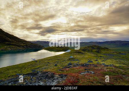 Sheepback Lake in den Talkeetna Mountains mit einem Wasserflugzeug, das in der Abenddämmerung am Ufer festgemacht wurde; Alaska, Vereinigte Staaten von Amerika Stockfoto