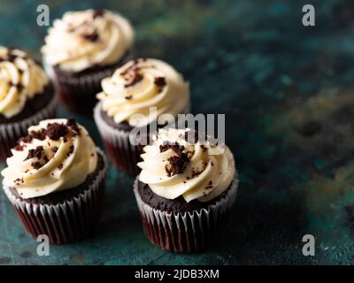 Festliches Dessert: Köstliche Schokoladen-Muffins, garniert mit Schlagsahne und geriebener dunkler Schokolade. Low-Angle-Ansicht. Restaurant, Süßwaren, Café, Stockfoto