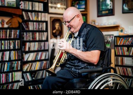 Ein Mann mit zwei Gliedmaßenamputationen, der zu Hause Trompete spielt Albert, Alberta, Kanada Stockfoto