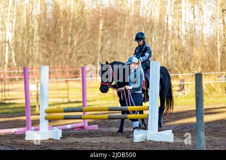 Ein Trainer, der mit einem jungen Mädchen mit Zerebralparese während einer Hippotherapiesitzung arbeitet; Westlock, Alberta, Kanada Stockfoto