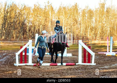 Ein Trainer, der mit einem jungen Mädchen mit Zerebralparese während einer Hippotherapiesitzung arbeitet; Westlock, Alberta, Kanada Stockfoto