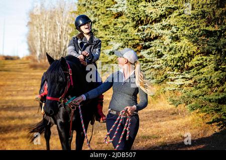 Ein Trainer, der mit einem jungen Mädchen mit Zerebralparese während einer Hippotherapiesitzung arbeitet; Westlock, Alberta, Kanada Stockfoto