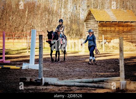 Ein Trainer, der mit einem jungen Mädchen mit Zerebralparese während einer Hippotherapiesitzung arbeitet; Westlock, Alberta, Kanada Stockfoto