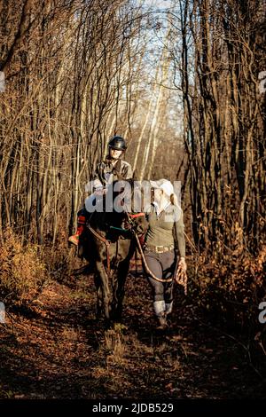 Ein junges Mädchen mit Zerebralparese und ihr Trainer, der mit einem Pferd während einer Hippotherapie auf einem Trail-Ritt arbeitet; Westlock, Alberta, Kanada Stockfoto