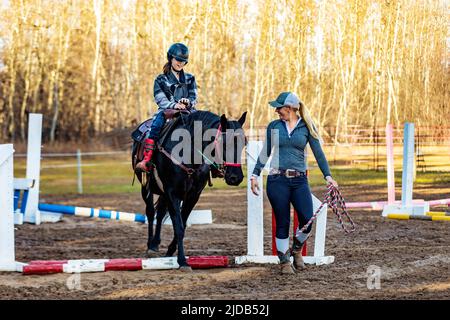 Ein Trainer, der mit einem jungen Mädchen mit Zerebralparese während einer Hippotherapiesitzung arbeitet; Westlock, Alberta, Kanada Stockfoto