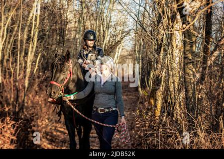 Ein junges Mädchen mit Zerebralparese und ihr Trainer, der mit einem Pferd während einer Hippotherapie auf einem Trail-Ritt arbeitet; Westlock, Alberta, Kanada Stockfoto