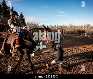 Ein Trainer, der mit einem jungen Mädchen mit Zerebralparese während einer Hippotherapiesitzung arbeitet; Westlock, Alberta, Kanada Stockfoto