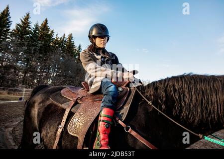 Ein junges Mädchen mit Zerebralparese, das während einer Hippotherapie auf einem Pferd reitet; Westlock, Alberta, Kanada Stockfoto