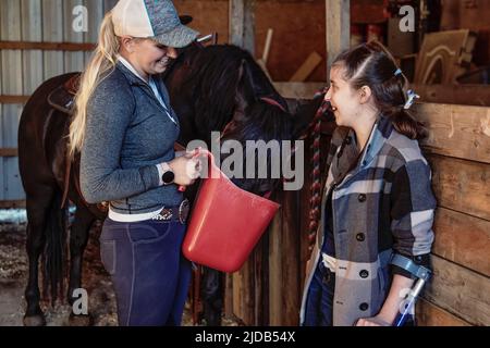 Ein junges Querschnittslähmung füttert ein Pferd mit ihrem Trainer während einer Hippostherapie-Sitzung; Westlock, Alberta, Kanada Stockfoto