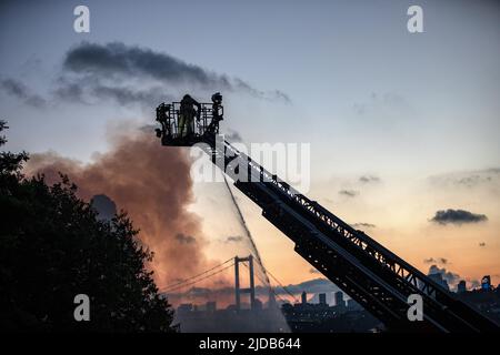 Istanbul, Türkei. 19.. Juni 2022. Die Feuerwehrleute löschen das Feuer von der Leiter des Löschfahrzeugs aus. Das Feuer, das in dem 2-stöckigen Holzgebäude in den Wäldern in der Beylerbeyi Sair Asaf Halet-Croebi-Straße in Uskudar, Istanbul, ausbrach, wurde nach etwa 1 Stunden Eingreifen der Feuerwehrleute unter Kontrolle gebracht. Kredit: SOPA Images Limited/Alamy Live Nachrichten Stockfoto