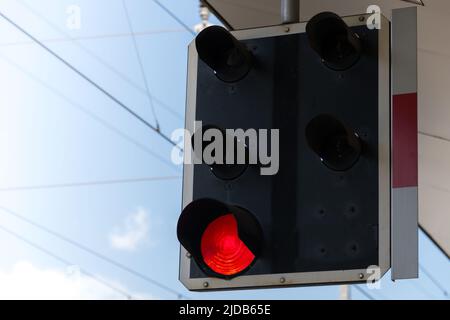 Nahaufnahme einer Bahnsignalampel mit rotem Licht auf einer Plattform gegen blauen teilweise bewölkten Himmel als Konzept für Probleme mit Verbindungen zu Stockfoto