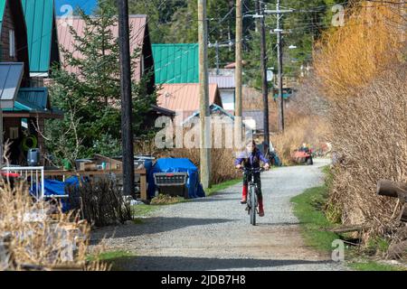 Ein junges Mädchen fährt mit dem Fahrrad den Weg in Tenakee Springs, Alaska. Reguläre Kraftfahrzeuge sind im kleinen südöstlichen Dorf nicht erlaubt Stockfoto