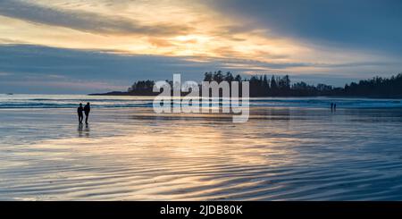 Die Leute genießen es, bei Ebbe am Long Beach bei Sonnenuntergang zu spazieren, dem größten und längsten Strand im Pacific Rim National Park Reserve an der Westküste... Stockfoto