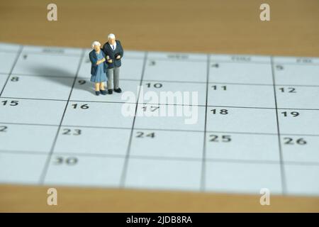 Miniatur Menschen Spielzeug konzeptuelle Fotografie. Älteres Paar, das über dem Kalender steht. Dating-Konzept. Bildfoto Stockfoto