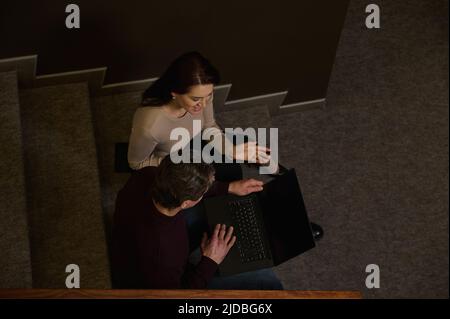 Draufsicht auf ein Team aus stolzen, selbstbewussten Geschäftspartnern mittleren Alters, Kollegen, stilvollen Männern und Frauen, die auf Treppen sitzen und sich unterhalten und gemeinsam arbeiten Stockfoto