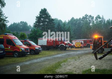 Treuenbrietzen, Deutschland. 20.. Juni 2022. Regen befällt das Einsatzgebiet bei Treuenbrietzen, das für Feuerwehr, THW und Polizei eingerichtet wurde. Heftige Regenfälle haben am frühen Montagmorgen im Kampf gegen zwei große Waldbrände in Brandenburg Abhilfe gebracht. Zunächst brannten bei Treuenbrietzen – 80 Kilometer südwestlich von Berlin – noch 135 Hektar Wald in der Nacht, so Beamte am Tatort. Kurz nach 7:00 Uhr wurde der Regen jedoch schwerer. Das Regenradar zeigte auch Regen und Gewitter für die nächsten Stunden an. Quelle: Annette Riedl/dpa/Alamy Live News Stockfoto